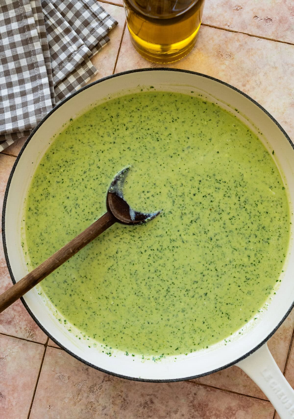 a pot of the creamy pesto sauce with a spoon resting inside.