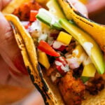 a fish taco held up to show toppings.