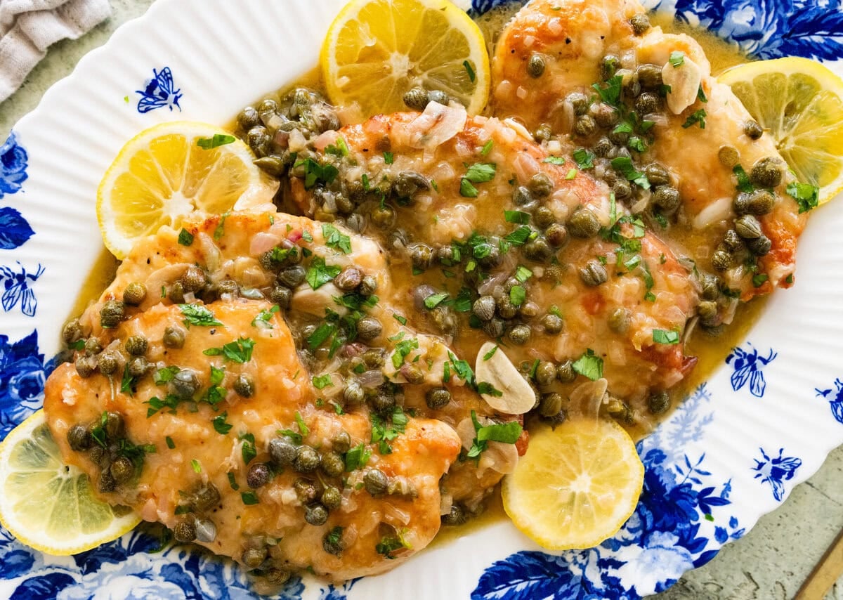 Lemon caper chicken on a serving dish garnished with lemon slices.