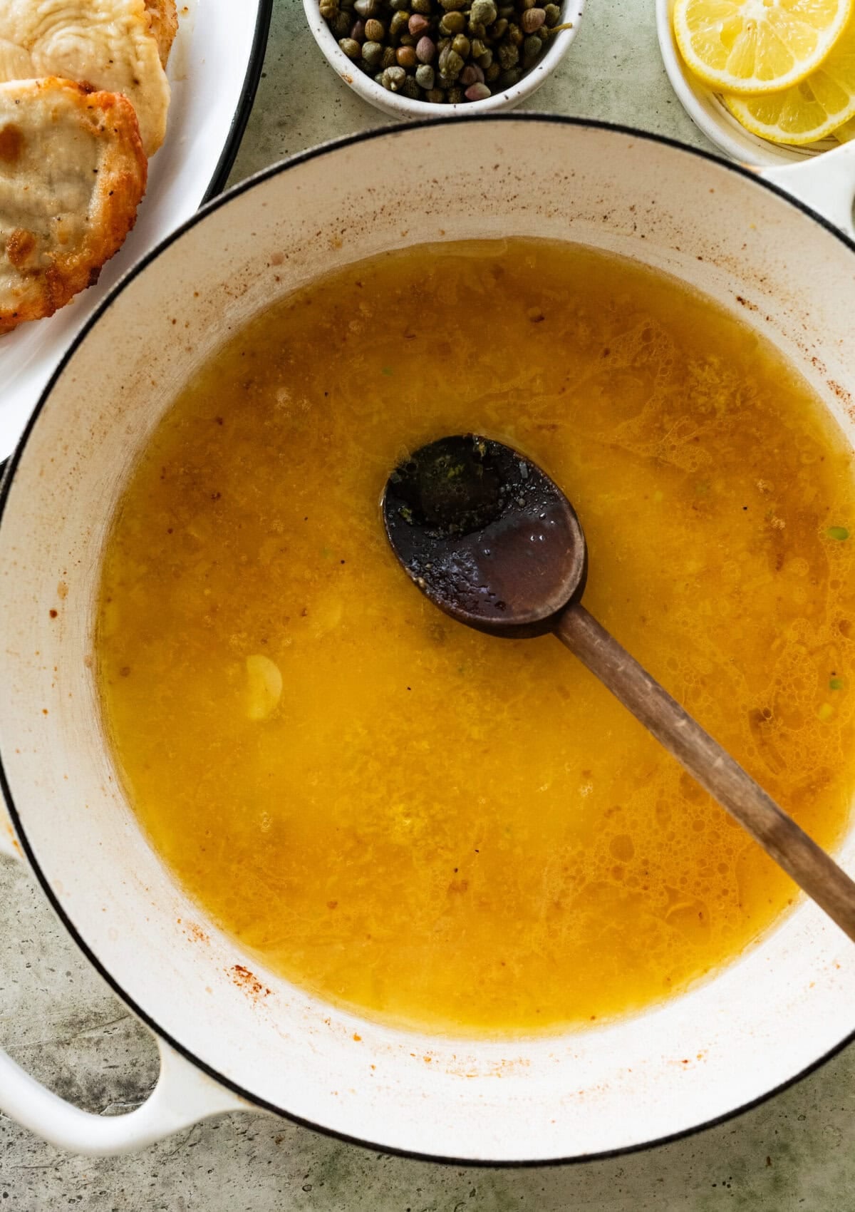 Sauce simmering in the skillet with a wooden spoon resting inside. 