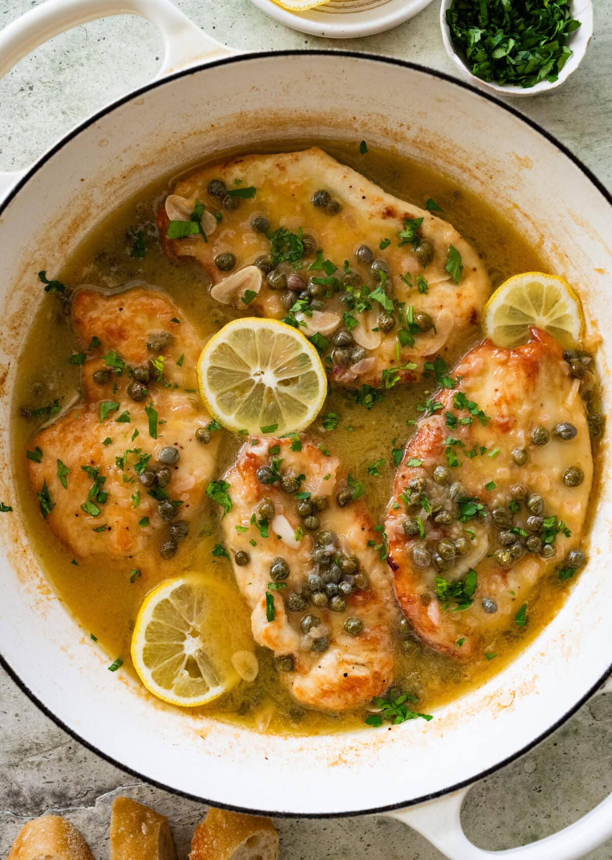 Lemon caper chicken in a skillet garnished with lemon slices. 