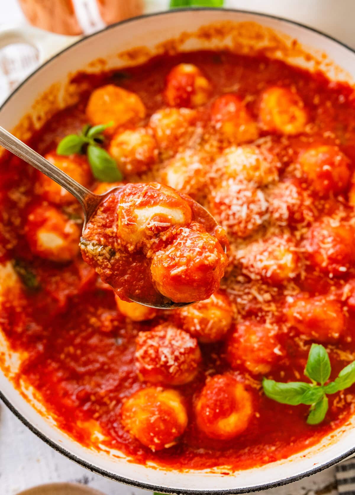 Ricotta gnudi in a bowl with sauce, and a fork holding some.