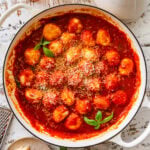 Ricotta gnudi in a skillet after cooking with sauce and garnish.