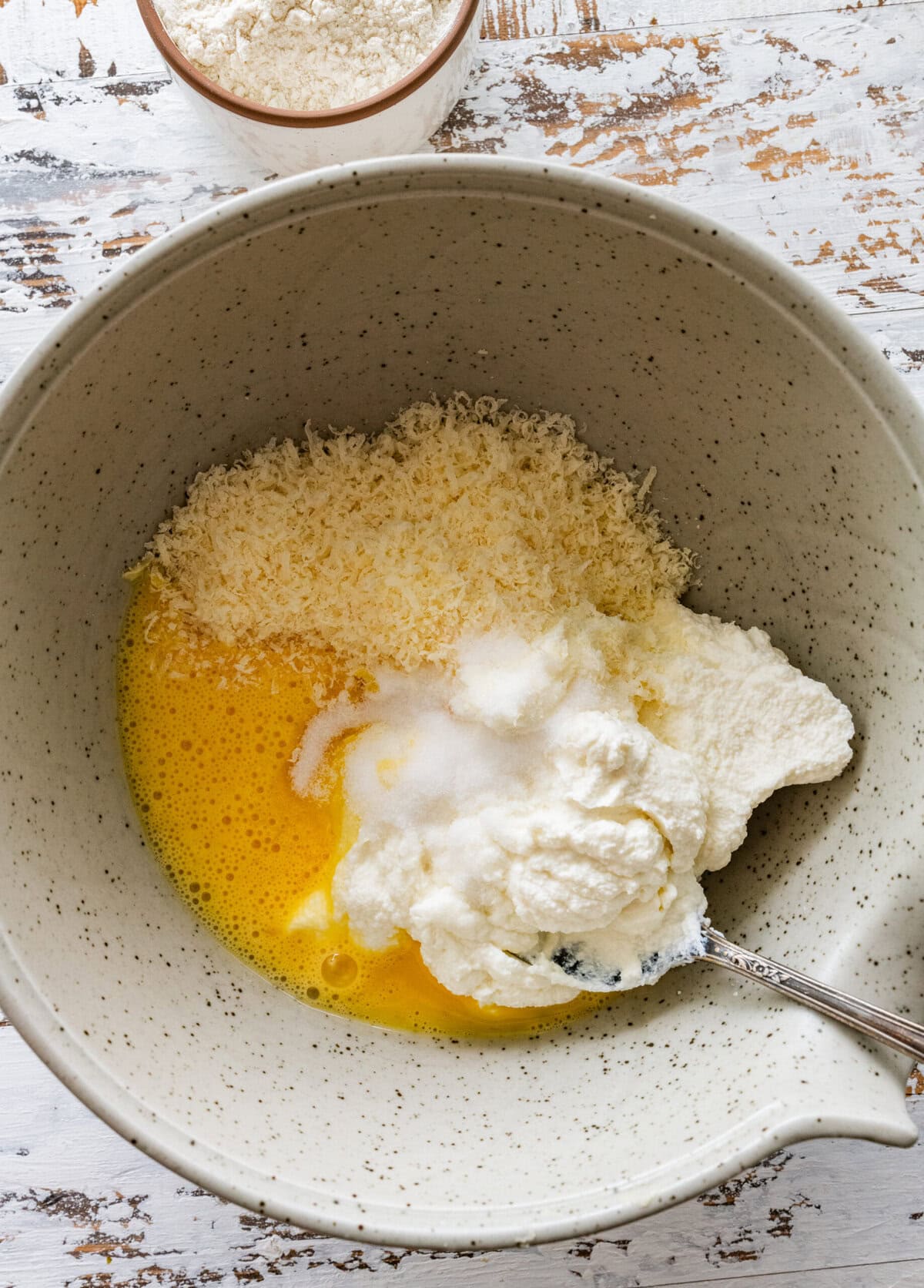 Drained ricotta, Parmesan, eggs, and salt in a bowl.