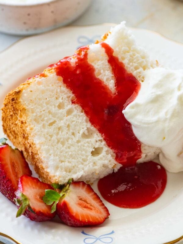 slice of angel food cake with strawberry sauce, whipped cream, and fresh strawberries.