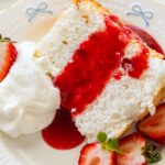 slice of angel food cake with strawberry sauce and fresh strawberries.