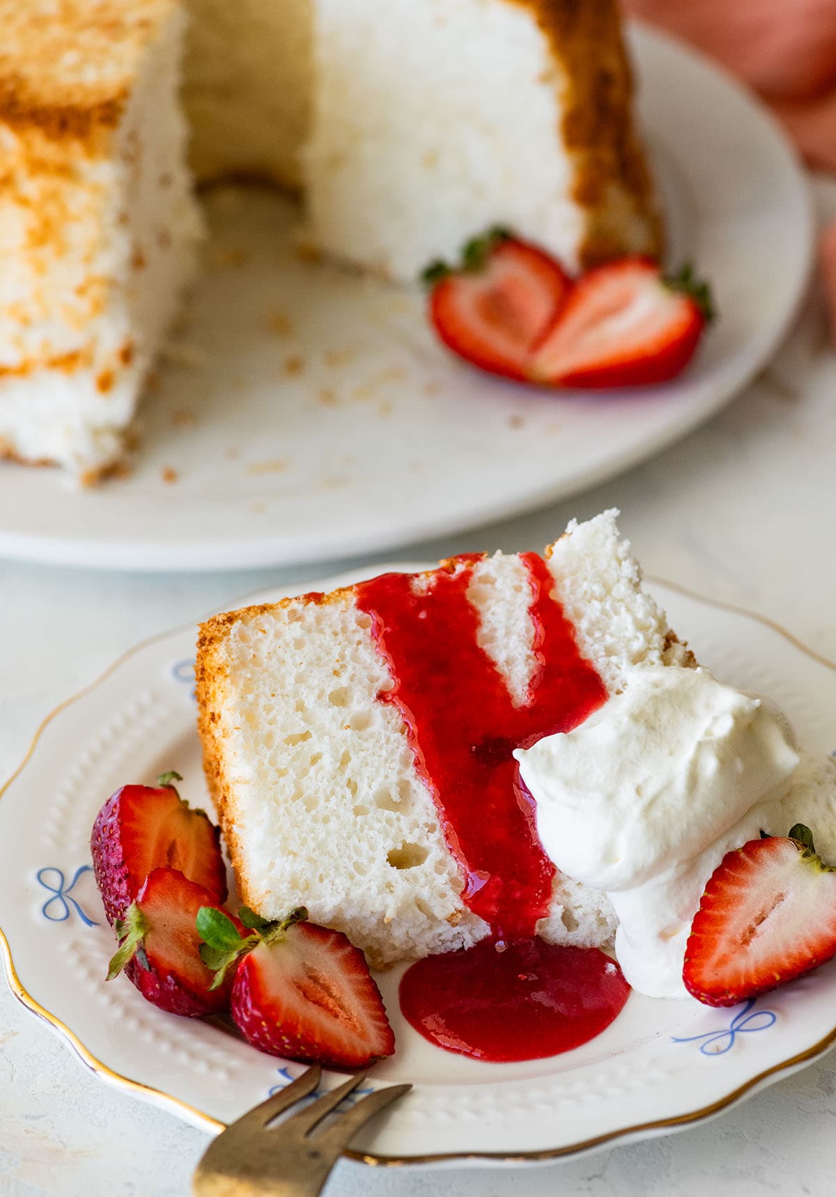 slice of angel food cake with strawberry sauce and fresh strawberries.