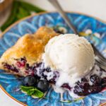 scoop of vanilla ice cream melting on top of a slice of blueberry galette.