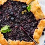 cutting a slice of blueberry galette with a knife.