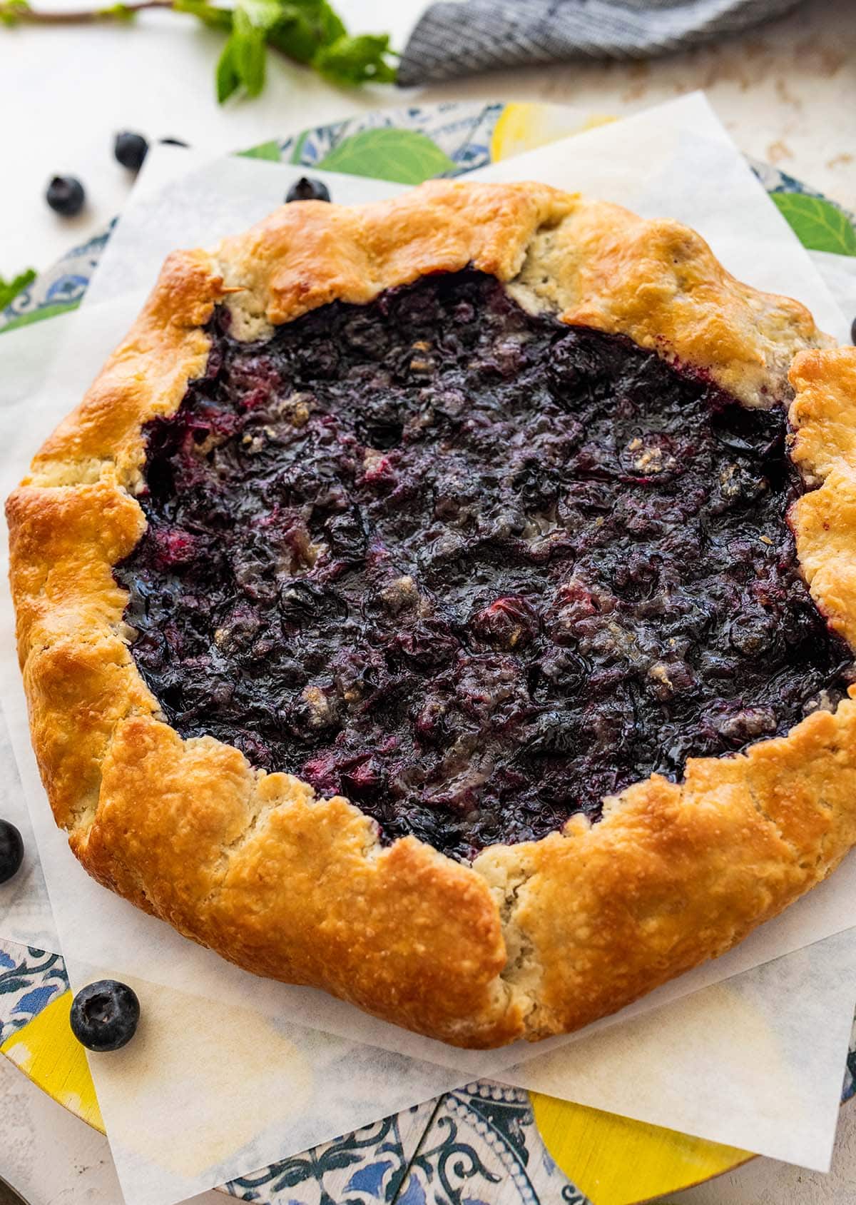 baked blueberry galette on parchment paper with fresh blueberries.