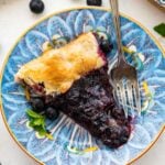 slice of blueberry galette and a fork on a blue floral plate.
