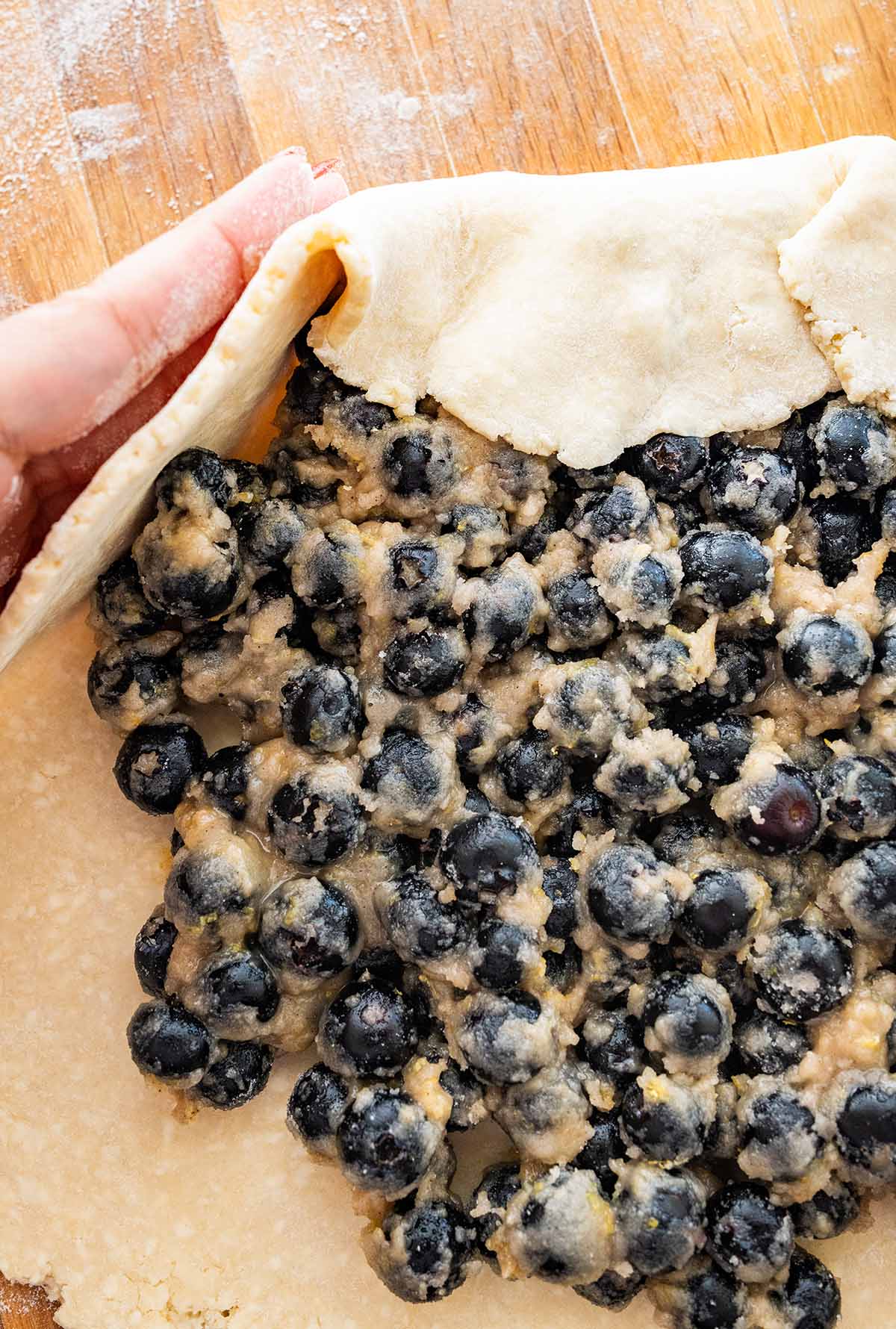 folding the edges of the pastry over the blueberry filling.