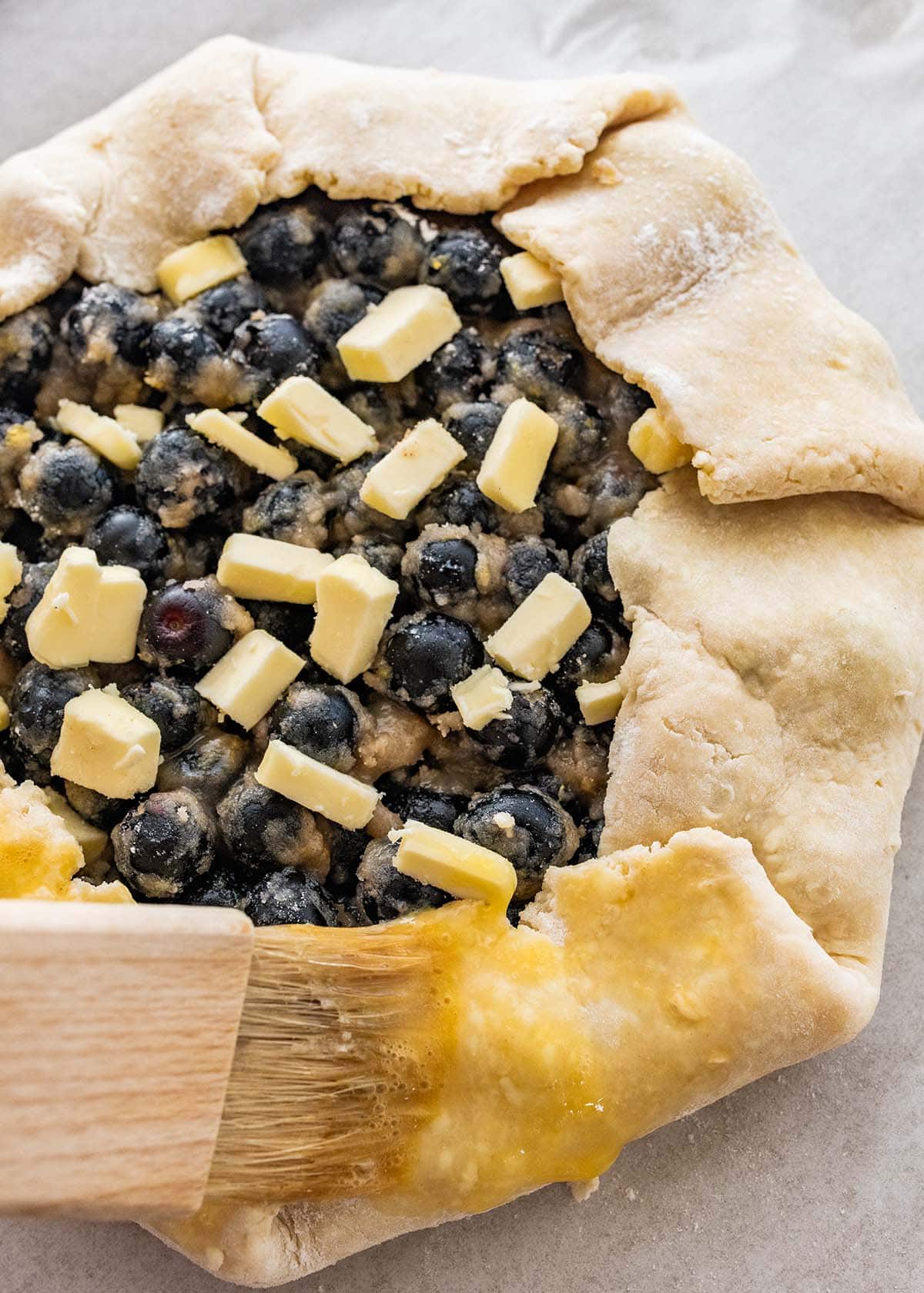 brushing a blueberry galette with beaten egg.