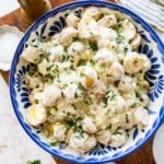 blue and white bowl of creamy potato salad garnished with tarragon.