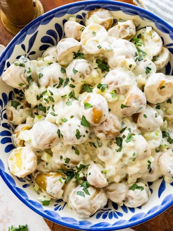 blue and white bowl of creamy potato salad garnished with tarragon.