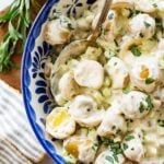 blue and white bowl of creamy potato salad with a striped napkin.