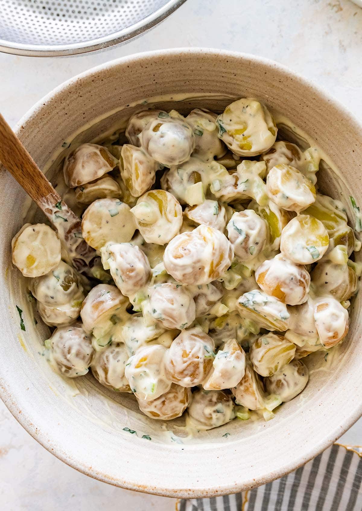 Yukon Gold potatoes tossed with creamy dressing in a white bowl.