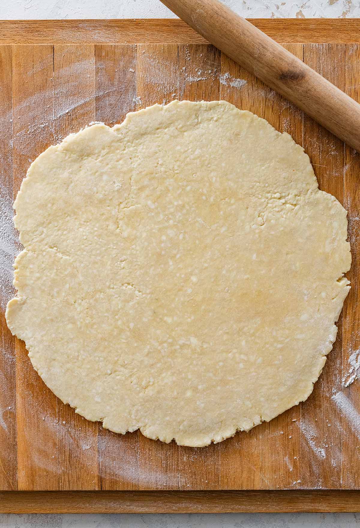 rolled out pastry circle on a flour-dusted wooden cutting board.
