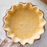 pastry in a deep, fluted pie dish with a rolling pin nearby.