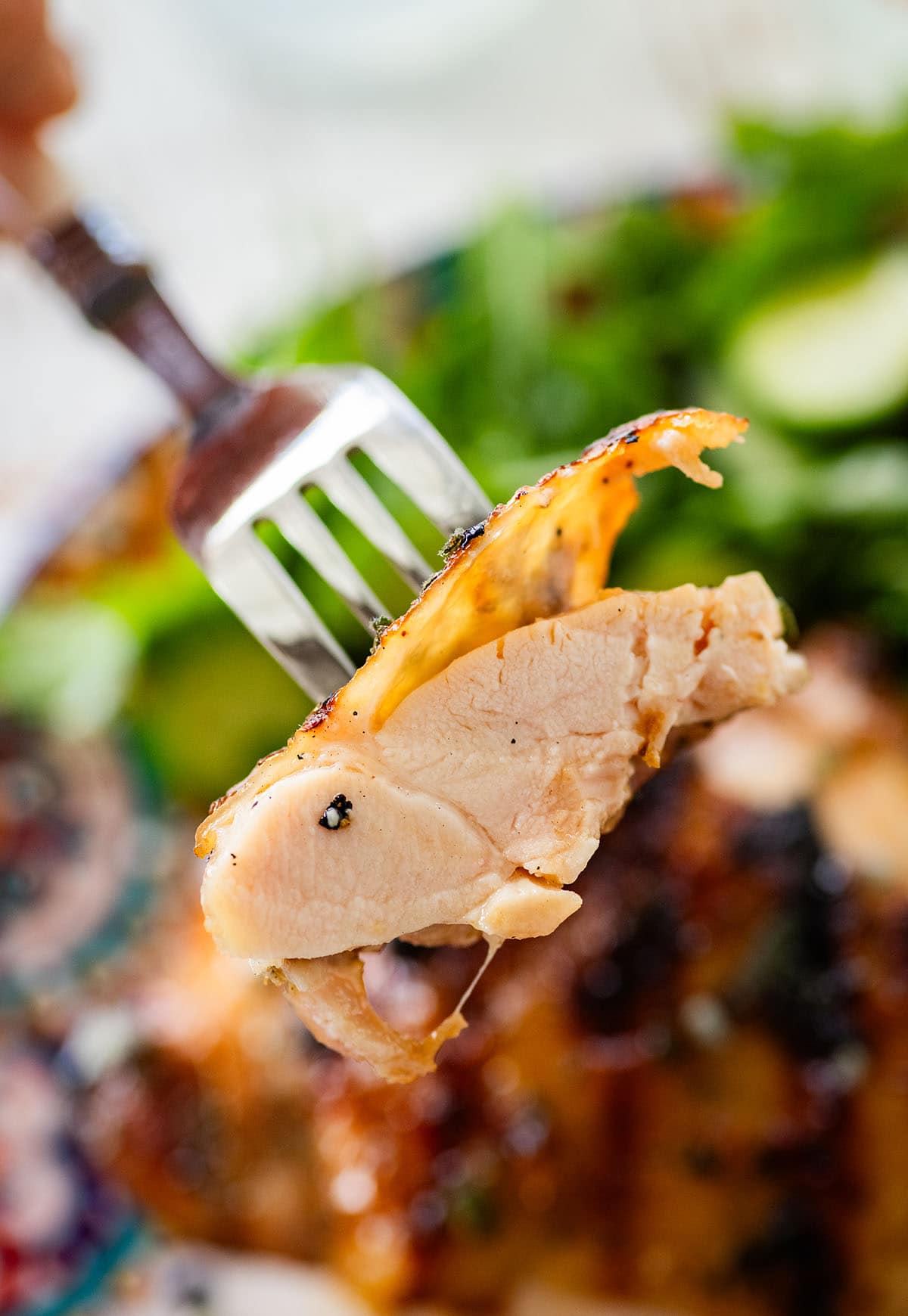 holding a forkful of moist grilled chicken thigh.