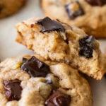 A half eaten cookie resting on top of another cookie with more nearby.