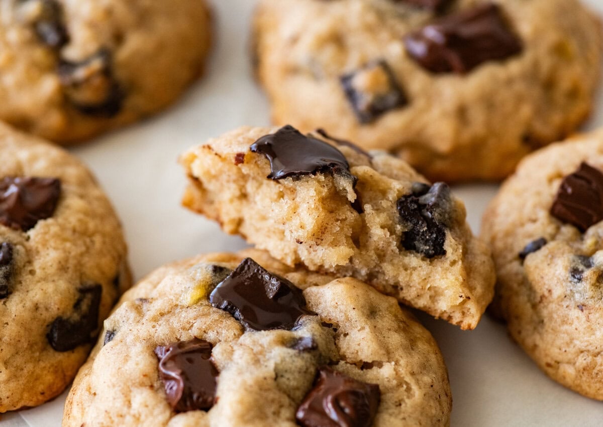 A half eaten cookie resting on top of another cookie with more nearby.