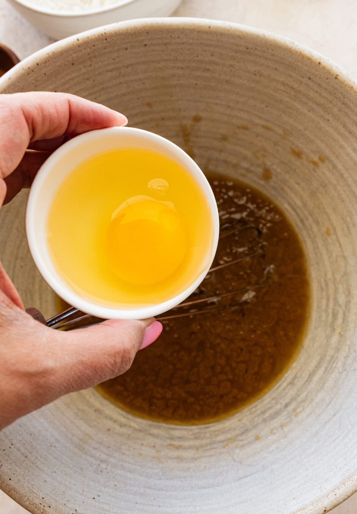 A bowl with an egg held over the larger bowl of