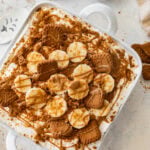 Biscoff banana pudding in a baking dish with more ingredients nearby.