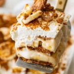 A slice of biscoff banana pudding held over the baking dish.