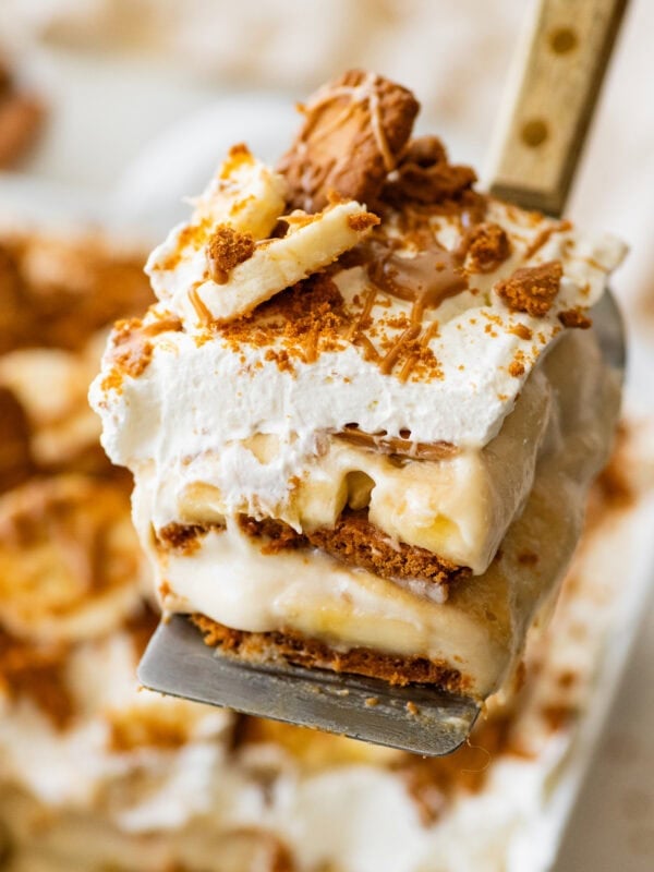 A slice of biscoff banana pudding held over the baking dish.