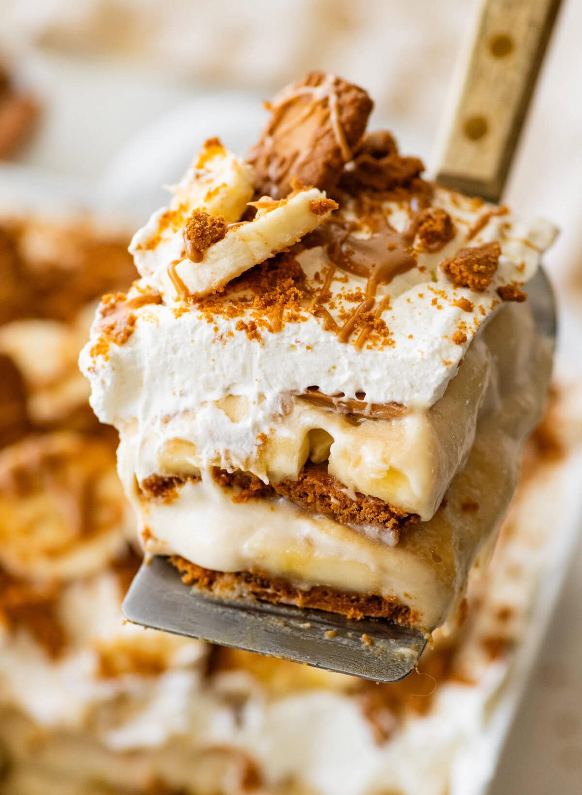 A slice of biscoff banana pudding held over the baking dish.
