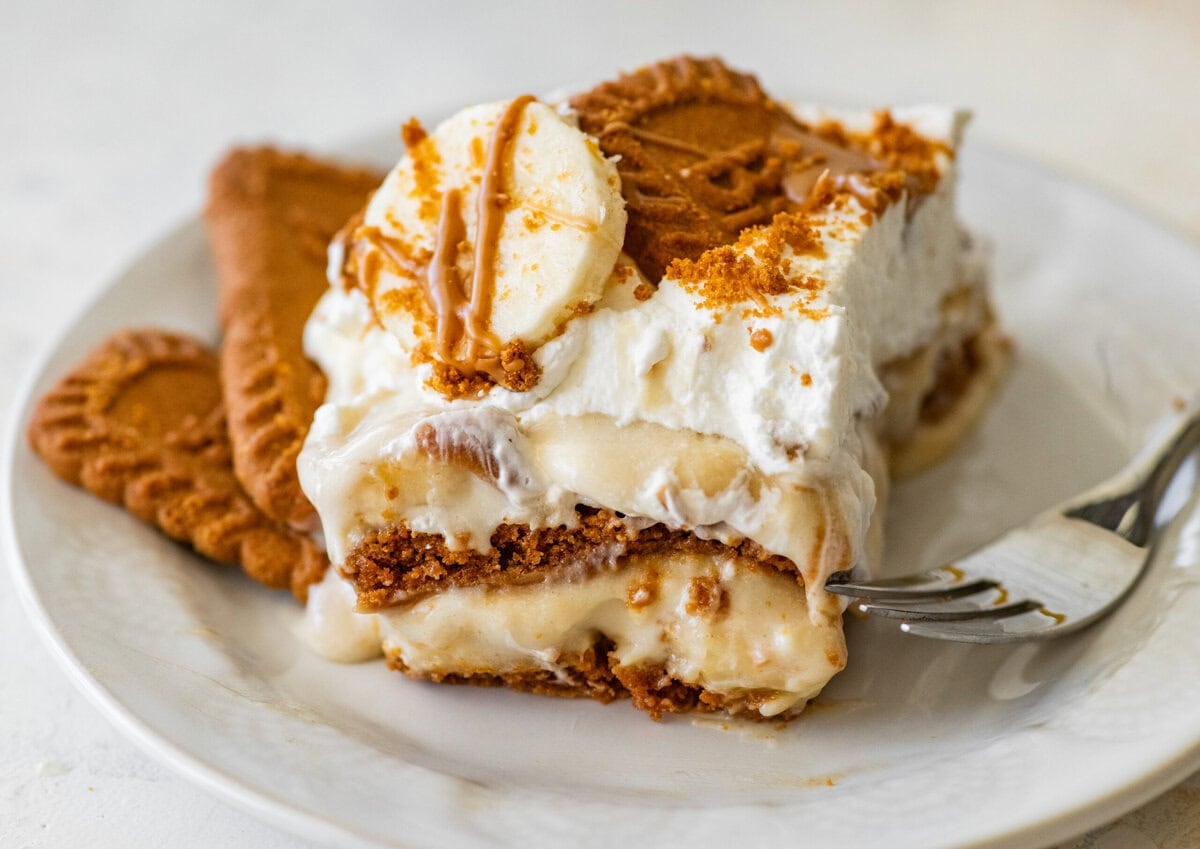 A slice of the pudding on a dish with biscoff cookies and a fork nearby.