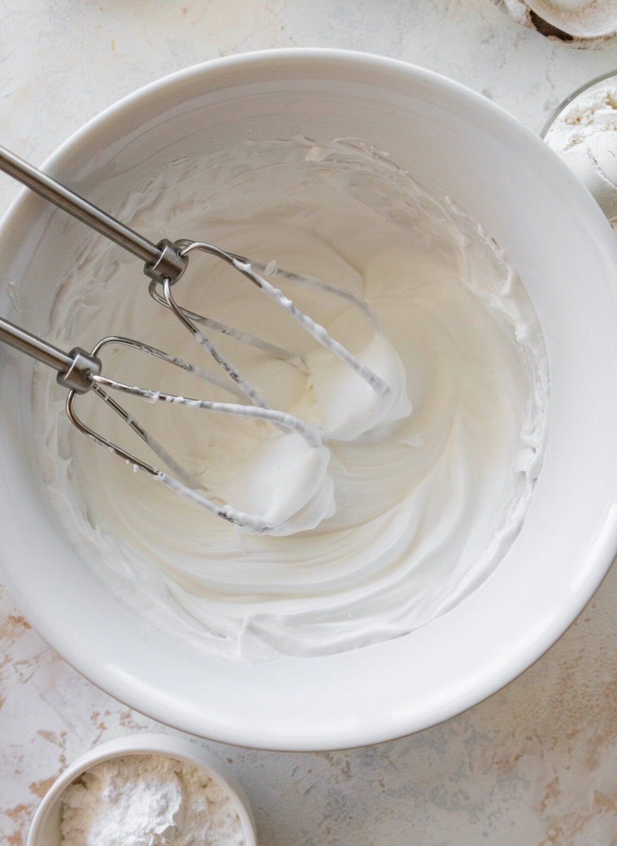 Beaters in a bowl with whipped egg whites.
