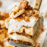 A slice of biscoff banana pudding held over the baking dish.