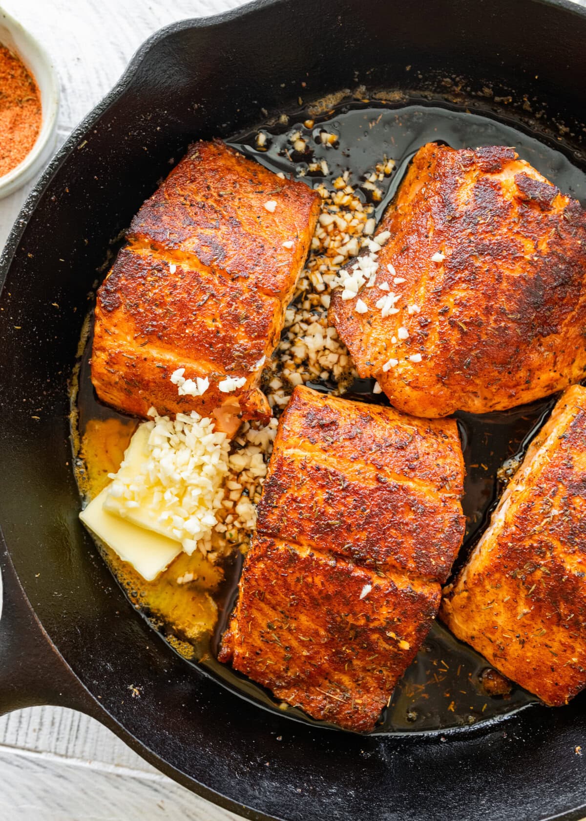Salmon fillets in a cast iron pan with garlic and butter added.