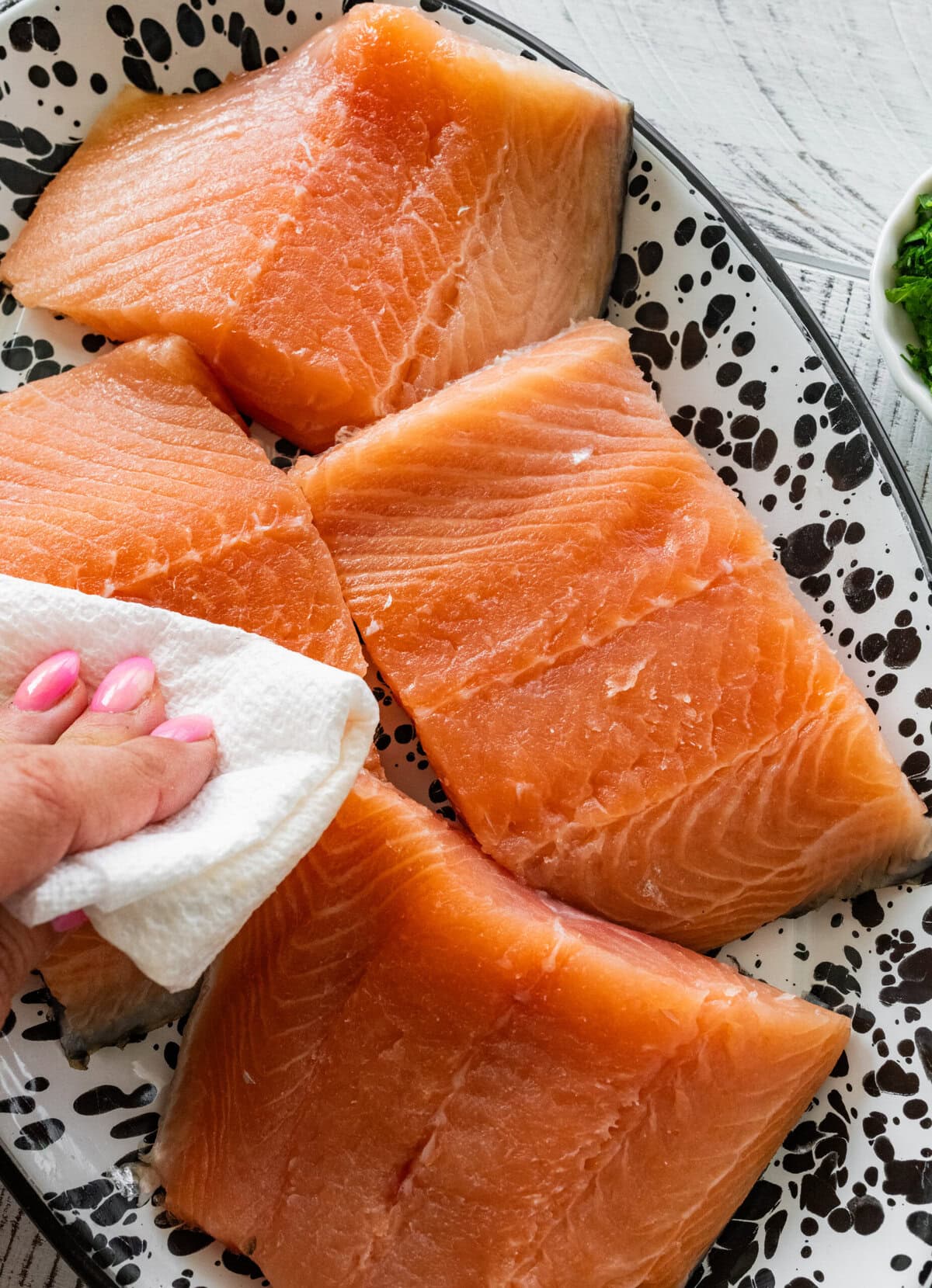 Patting salmon with a paper towel.