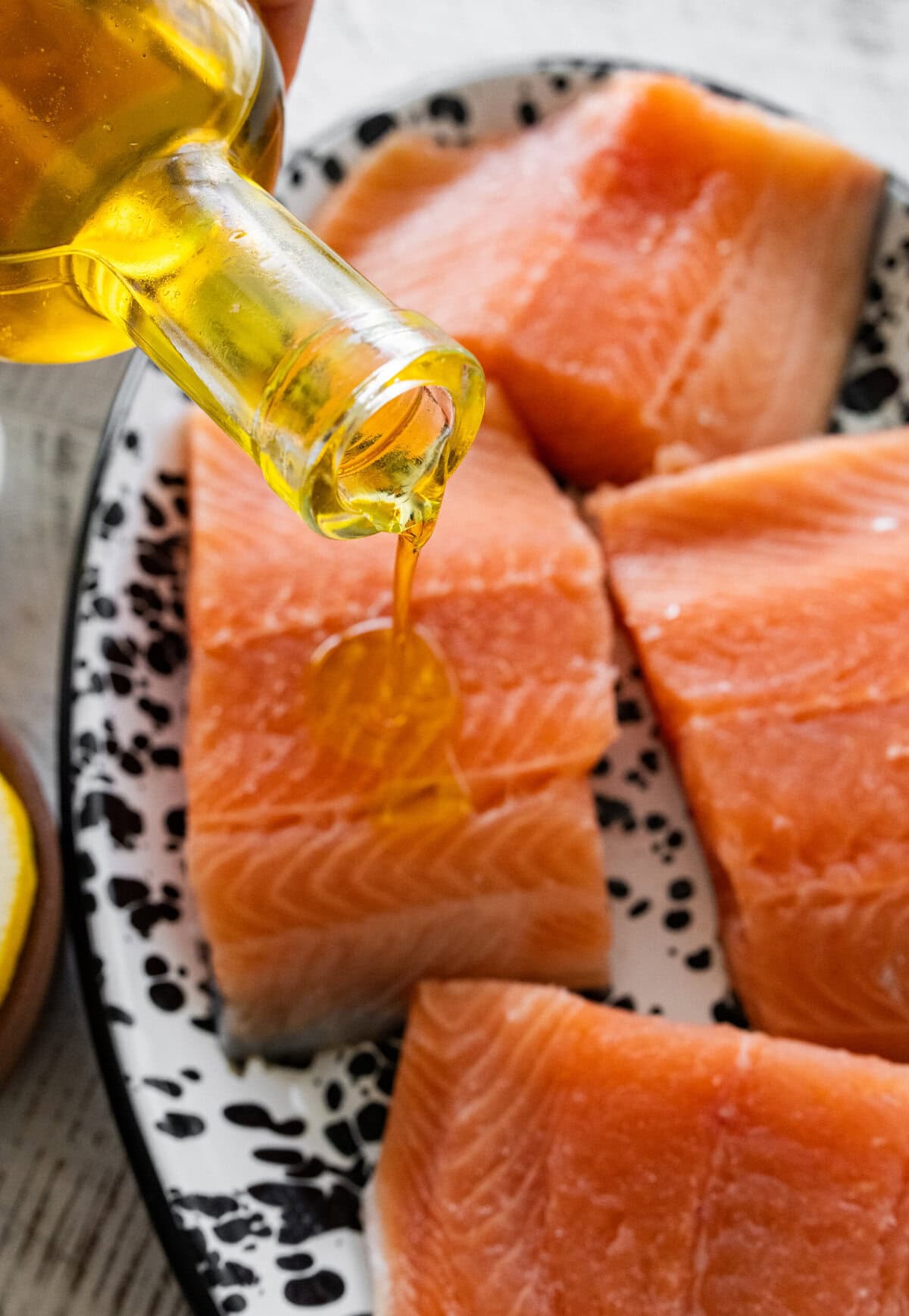 Drizzling olive oil over salmon.
