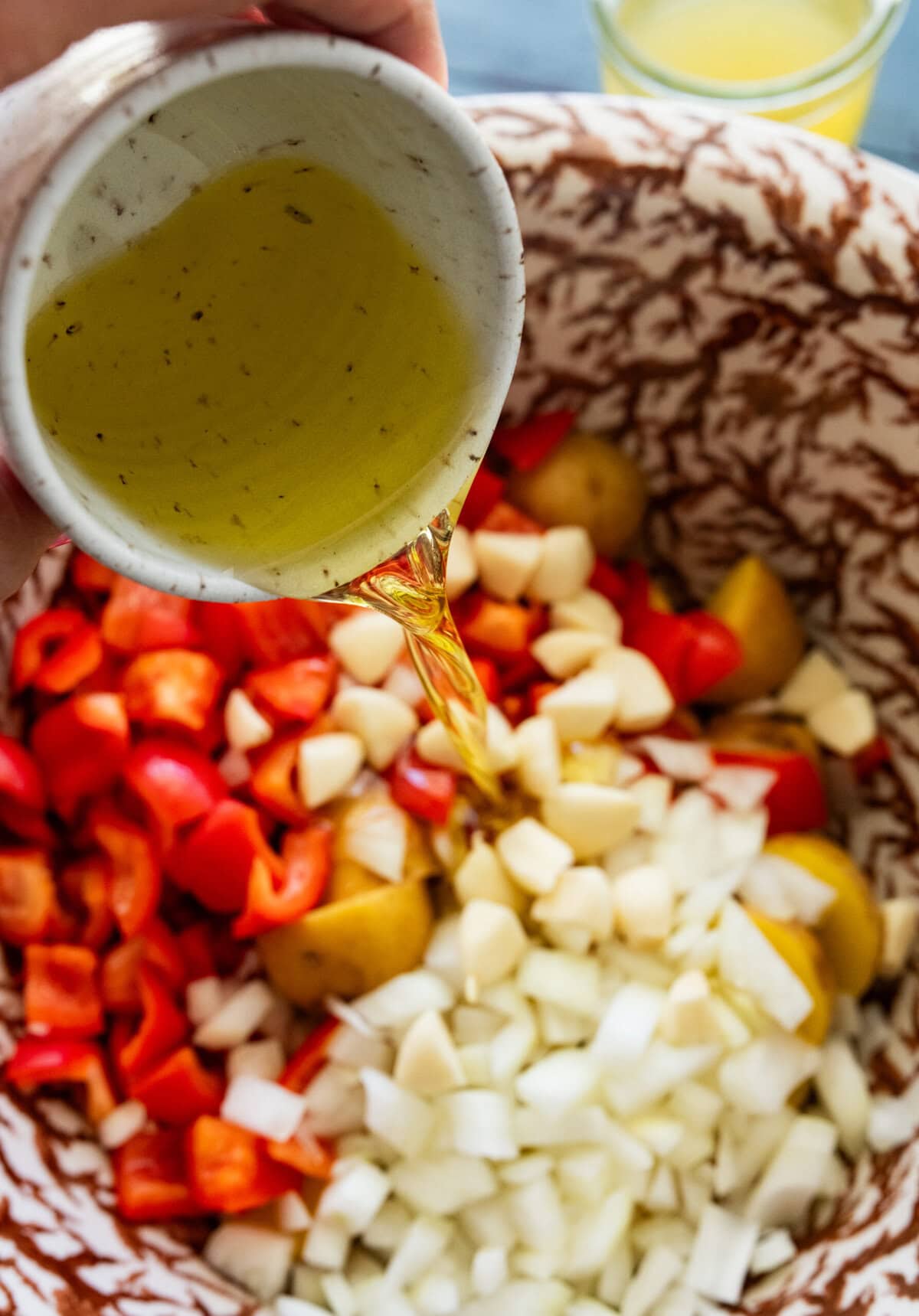 Olive oil being poured into the bowl of veggies.