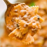 A forkful of beef and bowtie pasta held over a bowl of more pasta.