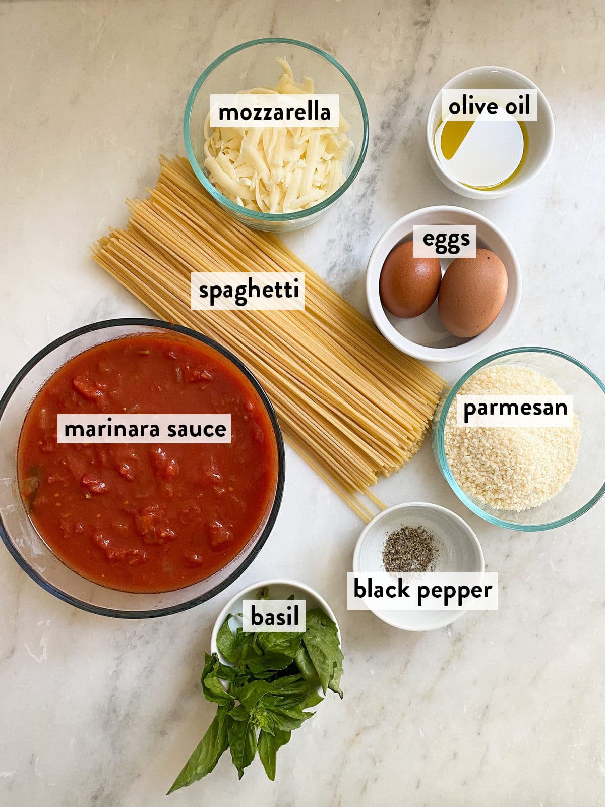 bowls of ingredients for fried spaghetti on a marble surface.