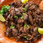 Shredded beef barbacoa on a large dish with garnish.