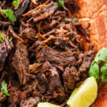 Shredded beef barbacoa on a large dish with garnish.