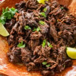 Shredded beef barbacoa on a large dish with garnish.