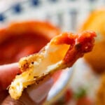 A hand holding a ravioli with one bite taken out.