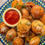 A plate of fried ravioli with garnish and a bowl of marinara sauce.