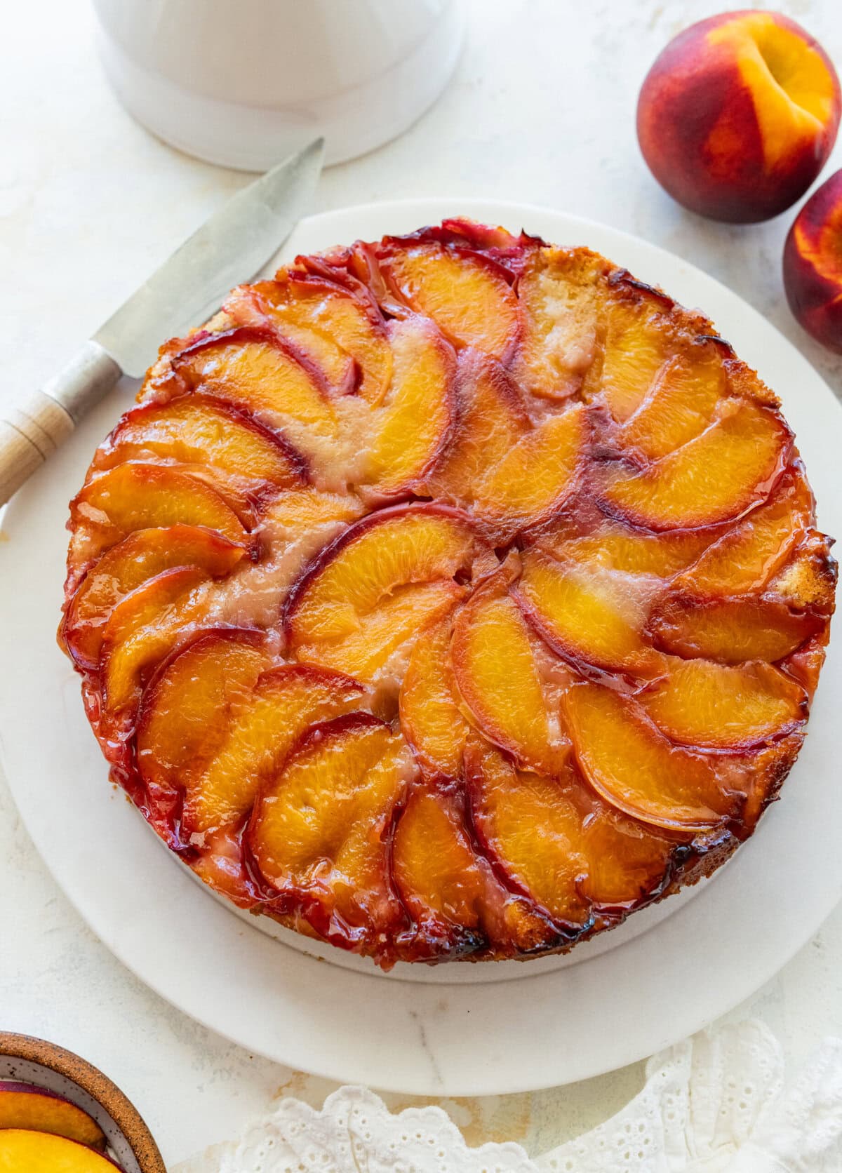 Peach upside down cake on a serving dish with ingredients nearby,