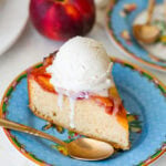 A slice of cake on a plate with a scoop of ice cream on top, a spoon resting on the edge, and more ingredients nearby.