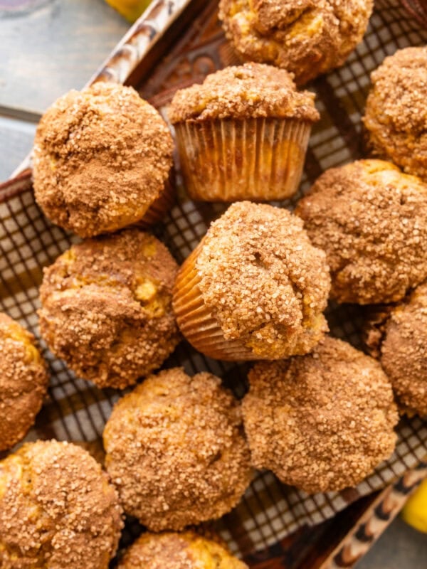 A tray of pumpkin banana muffins with bananas and pumpkins nearby.