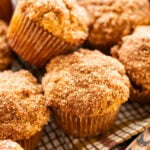 A tray of pumpkin banana muffins with bananas and pumpkins nearby.