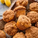 A tray of pumpkin banana muffins with bananas and pumpkins nearby.